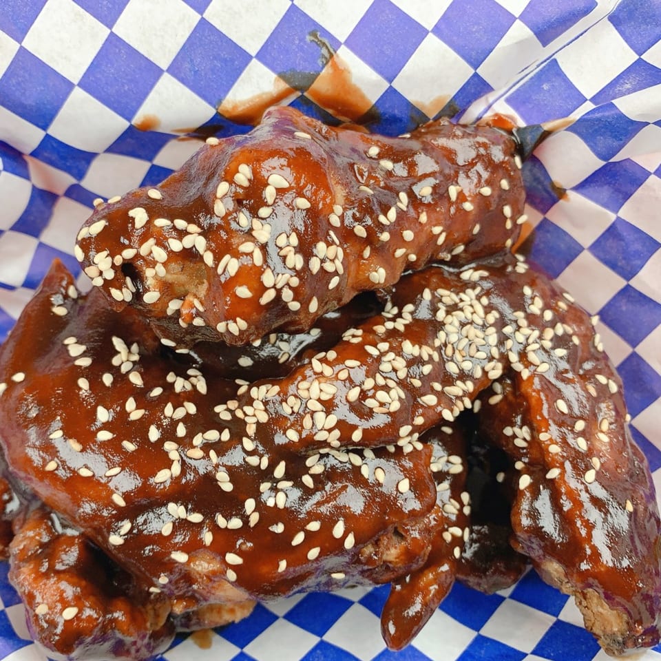 Barnrau Thai Halal Cuisine's chicken wings coated in a dark, glossy sauce and sprinkled with sesame seeds.