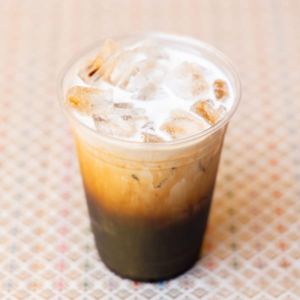 Iced Thai milk tea with a dark bottom layer, light brown middle, and white top with ice.